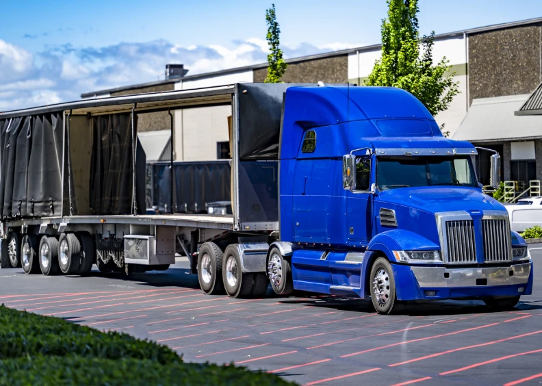 Blue semi-truck parked near warehouse